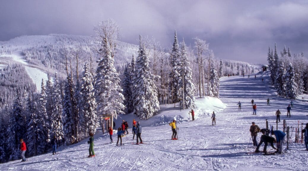 Far away shot of lots of people skiing on a slope